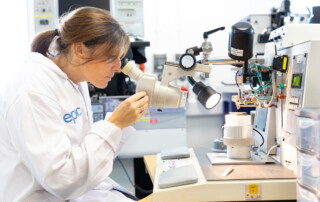 Photography of a scientist at work using specialist microscopy within the photonics industrty in Devon.